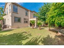 View of the backyard showcasing the lawn, trees, and the two-story home with multiple windows at , Gilbert, AZ 85234