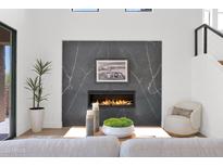 Contemporary living room features a sleek fireplace with stone surround, a plush armchair, and modern decor at 19550 N Grayhawk Dr # 1039, Scottsdale, AZ 85255