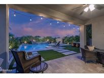 Inviting covered patio with outdoor seating overlooking a beautiful pool with waterfall feature and manicured landscaping at 2339 E Questa Dr, Phoenix, AZ 85024