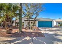 Charming home featuring desert landscaping, a blue garage door, and a well-maintained front yard at 2421 E Dragoon Ave, Mesa, AZ 85204
