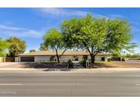 Charming single-story home featuring desert landscaping, mature trees, and a tile roof at 5112 E Cholla St, Scottsdale, AZ 85254