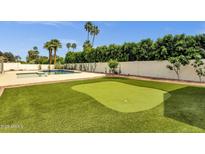 Inviting backyard featuring a putting green, pool, and lush landscaping, perfect for outdoor relaxation and entertainment at 5827 E Larkspur Dr, Scottsdale, AZ 85254
