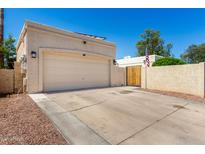 Beige garage with a concrete driveway complemented by a wooden gate and tan painted walls at 630 E Jensen St # 154, Mesa, AZ 85203