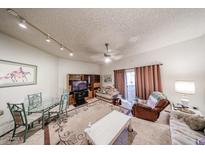 Comfortable living room with a glass top dining table, sofa, ceiling fan, and sliding glass door at 10401 W Loma Blanca Dr, Sun City, AZ 85351