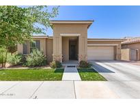 Charming home exterior featuring a well-manicured lawn and welcoming entrance, garage, and desert landscaping at 22495 E Silver Creek Ln, Queen Creek, AZ 85142