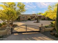 Beautiful home with a circular driveway, desert landscaping, and wrought iron gated entrance at 22610 N 80Th Pl, Scottsdale, AZ 85255