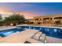 Inviting pool with baja step and travertine tile and outdoor seating area with fire pit at 22610 N 80Th Pl, Scottsdale, AZ 85255