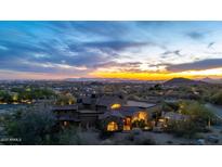 Stunning aerial view of the stone and stucco home with a tile roof set against a vibrant sunset backdrop at 3553 N Crystal Peak Cir, Mesa, AZ 85207