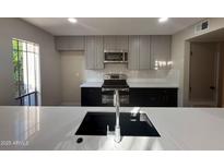 Updated kitchen with grey cabinets, black appliances, and modern backsplash at 5221 N 24Th St # 103, Phoenix, AZ 85016