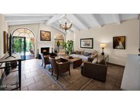 Inviting living room with a fireplace, neutral tones, and abundant natural light from the arched windows and doorway at 7955 E Chaparral Rd # 73, Scottsdale, AZ 85250