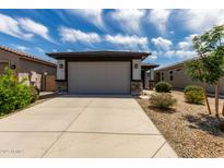Home exterior featuring a two car garage with a neutral door and stone accents at 17437 W Via De Luna Dr, Surprise, AZ 85387
