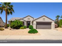 Charming single-story home featuring desert landscaping, a palm tree, and a two-car garage at 19892 N Shadow Mountain Dr, Surprise, AZ 85374