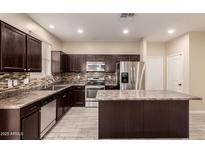 Modern kitchen with stainless steel appliances, island, and dark wood cabinetry at 7769 W Bonitos Dr, Phoenix, AZ 85035