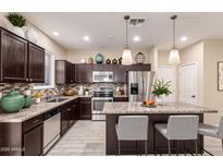 Modern kitchen features stainless steel appliances, dark wood cabinets, and a large island with seating at 7769 W Bonitos Dr, Phoenix, AZ 85035
