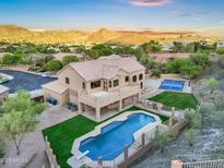 Expansive home with private pool, diving board, and tennis court nestled against a mountain backdrop at sunset at 14049 S 8Th St, Phoenix, AZ 85048