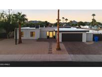 Inviting single-story home boasts desert landscaping, a brick driveway and desert mountain views at sunset at 3615 E Charter Oak Rd, Phoenix, AZ 85032