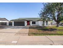 Charming single-story home with a well-maintained front yard, a black garage door, and a red front door at 7425 W Corrine Dr, Peoria, AZ 85381