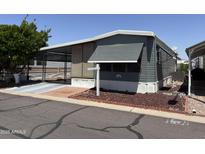 Charming single-story mobile home with covered parking, a tidy yard, and mature tree provides curb appeal at 8700 E University Dr # 1450, Mesa, AZ 85207