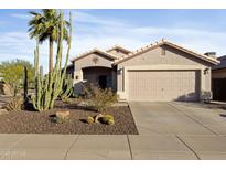 Charming home featuring desert landscaping, a two-car garage, and a welcoming front porch with a decorative sunburst at 2119 E Daley Ln, Phoenix, AZ 85024