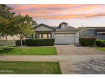 Charming home featuring a well-manicured front yard, brick driveway, and neutral-colored facade set against a sunset sky at 3163 E Austin Dr, Gilbert, AZ 85296