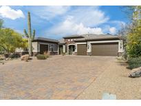 Charming home featuring a brick driveway, lush desert landscaping, and a three-car garage at 35971 N Prickley Pear Rd, Cave Creek, AZ 85331