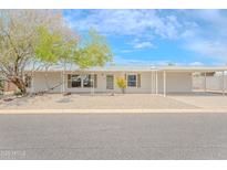 Inviting single-story home with a covered parking area and xeriscaped front yard featuring mature trees and desert plants at 16008 N 69Th Ln, Peoria, AZ 85382