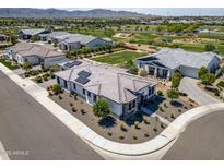 Stunning aerial view of a modern home featuring solar panels, landscaping, and a nearby golf course community at 17376 W Wildwood St, Surprise, AZ 85388