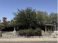 Modest single story home behind a decorative block wall with a tree filled front yard at 3112 W Taylor St, Phoenix, AZ 85009
