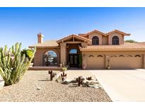 Inviting home featuring desert landscaping, a tile roof, arched windows and a three car garage at 3538 E Squawbush Pl, Phoenix, AZ 85044