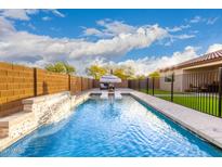 A backyard pool with a waterfall feature and lounge chairs offers a relaxing outdoor space at 7829 W Warner St, Phoenix, AZ 85043