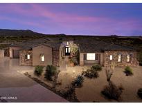 Stunning home exterior showcases desert landscaping, stone accents, and a tile roof under a vibrant sunset sky at 9936 E Winter Sun Dr, Scottsdale, AZ 85262
