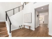 Bright foyer featuring hardwood floors, staircase with iron railing, and view to living area at 11891 N 147Th Dr, Surprise, AZ 85379