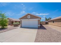 Tan home exterior with a two car garage, low maintenance landscaping, and a concrete driveway at 15725 W Lundberg St, Surprise, AZ 85374