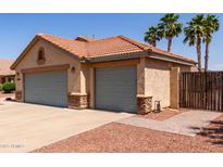 Exterior shot of a three-car garage with desert landscaping and mature palm trees in the background at 1625 E Daisy St, Casa Grande, AZ 85122