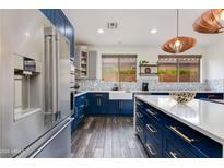Bright kitchen boasts blue lower cabinets, stainless steel appliances, and a farmhouse sink at 20713 N 91St Dr, Peoria, AZ 85382