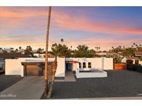 Exterior shot of a bright single-story home featuring desert landscaping, a modern garage, and an open patio at 10245 N 34Th Pl, Phoenix, AZ 85028