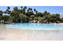 Lagoon-style community pool with sandy beach entry and lush landscaping at 1633 E Lakeside Dr # 143, Gilbert, AZ 85234