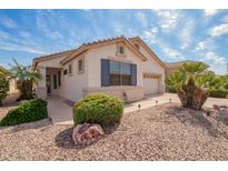 Charming home exterior with a well-manicured desert landscape, including a palm tree and rock accents at 18077 W Sammy Way, Surprise, AZ 85374