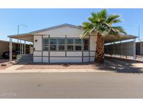 Charming single-story home featuring large windows, a covered carport, and a beautifully landscaped yard with a mature palm tree at 205 S Higley Rd # 300, Mesa, AZ 85206