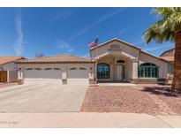 Charming single-story home featuring a three-car garage, desert landscaping, and American flag at 9566 E Plana Ave, Mesa, AZ 85212