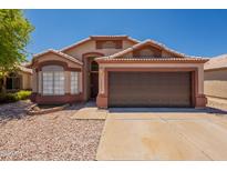 Charming single-story home featuring a two-car garage, desert landscaping, and neutral earth tone colors at 15642 N Naegel Dr, Surprise, AZ 85374