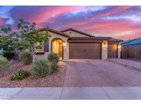 Charming single-story home with a three car garage, desert landscaping, and inviting curb appeal at dusk at 19873 W San Juan Ave, Litchfield Park, AZ 85340