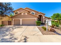 Charming tan home with a three-car garage, arched entry, and professionally landscaped front yard at 3581 W Ironwood Dr, Chandler, AZ 85226