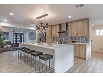 Modern kitchen with white quartz island, sleek lighting, wood cabinets, and black and white backsplash at 1539 W Puget Ave, Phoenix, AZ 85021