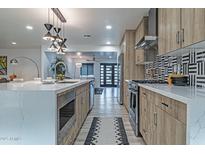 A modern kitchen features wood-tone cabinetry, quartz countertops, and a mosaic tile backsplash at 1539 W Puget Ave, Phoenix, AZ 85021