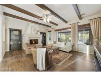 Bright living room features a fireplace, wooden beam ceiling, and a large window overlooking the backyard at 2727 S Balboa Dr, Gilbert, AZ 85295