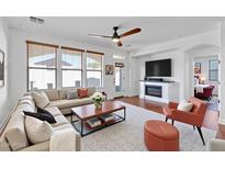 Bright living room features a fireplace, stylish furnishings, wood floors, and large windows at 29798 N 121St Dr, Peoria, AZ 85383