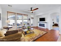 Open-concept living room with a fireplace and a view into the backyard at 29798 N 121St Dr, Peoria, AZ 85383