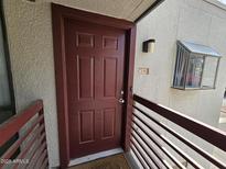 Inviting condo entrance with a sturdy red door, and decorative wall mount lighting and window features at 3420 W Danbury Dr # C218, Phoenix, AZ 85053