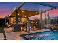 Outdoor pool features a covered lounge area with a bar, seating, and water feature at sunset at 6320 E Gloria Ln, Cave Creek, AZ 85331